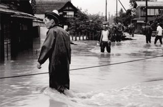 ロープを張り避難のための誘導をする地域住民