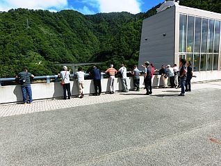 天端から山々の緑とながい百秋湖を眺める