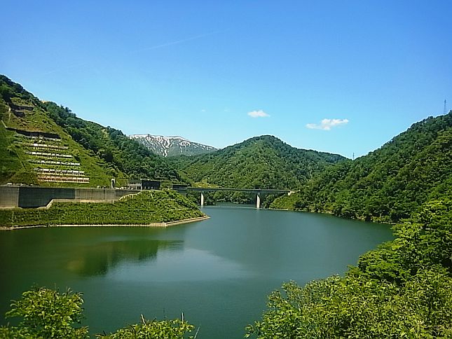 ダム堤体左岸から望む残雪の三体山と深緑のながい百秋湖（6月6日撮影）