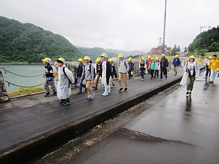 堤体（ダム本体）の上を歩きながら説明を受ける児童の皆さん