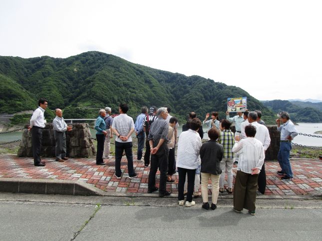 堤体上でダムの型式の説明を受ける皆さん