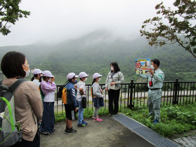 展望広場でダム湖の説明を聞く西郷第一小学校4年生