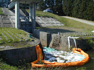 【最上川での灯油流出事故例】最上川に流れ込まないように、合流する手前の樋管（ひかん）にオイルフェンスを設置して吸着マットで灯油を回収。