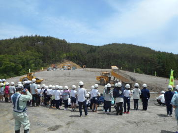 盛土用工事機械のデモ運転を見つめる生徒達